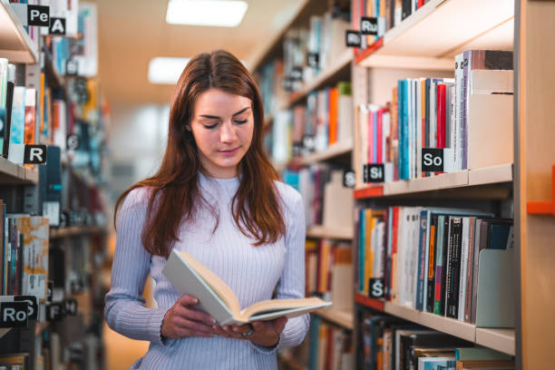 istock Caucasian Female Reading  Between Bookshelves In A Library 1491106771