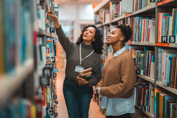 istock Mid Adult Hispanic Librarian Escorting A Student In A Library 1491106776