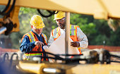 Two multiracial construction workers reviewing blueprint