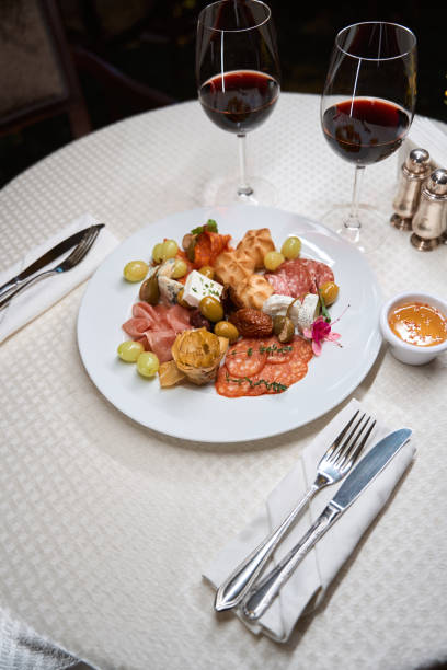 istock Plate with different snacks and red wine on white table in the restaurant 1491121074