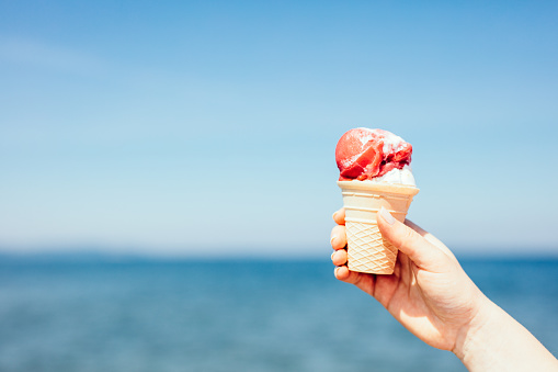 Ice cream in woman hand by the sea. Summertime