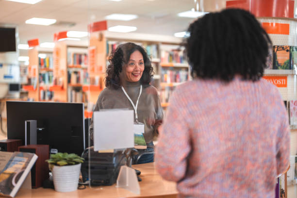 istock Mid Adult Hispanic Female Librarian Serving A Costumer 1491122025