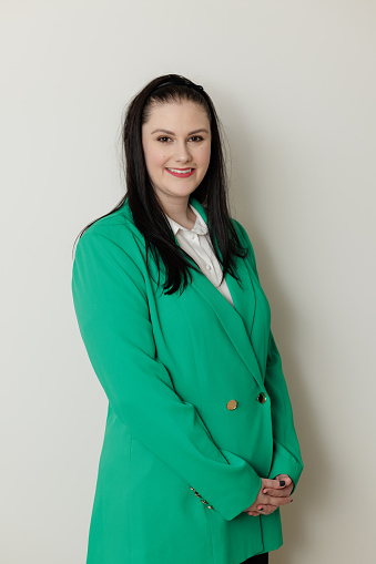 Smiling businesswoman in green jacket against a plain background