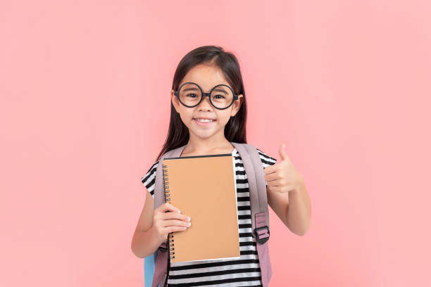 istock schoolgirl hugging book wearing backpack smiling isolated on pink background 1491127727