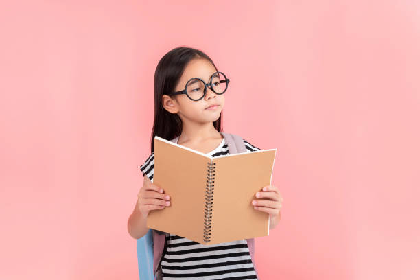 istock schoolgirl hugging book wearing backpack smiling isolated on pink background 1491127732