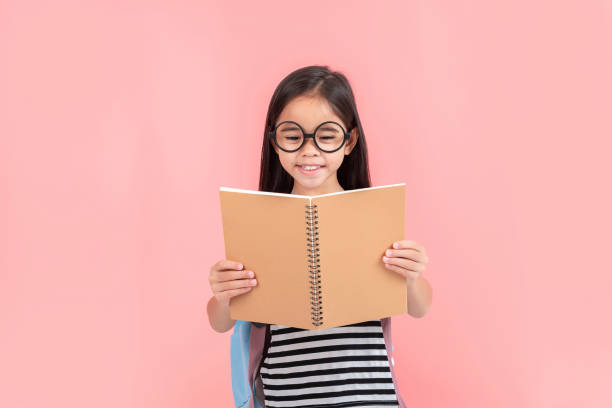 istock schoolgirl hugging book wearing backpack smiling isolated on pink background 1491127740