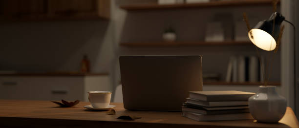 istock Modern workspace at night in a dark room with laptop, table lamp, and decor on a table 1491130418
