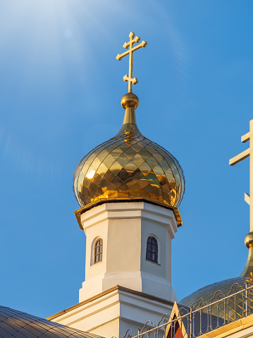 Gilded dome with a cross of an Orthodox church against a blue clear sky. Golden church dome on blue background