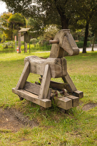 rustic toy in a park, rocking chair in the shape of a wooden horse, background with nature, decoration object for children, details of a craft object