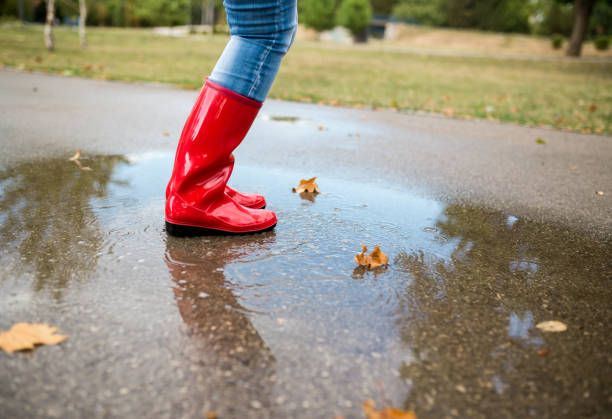 Rubber boots are jumping into a big puddle with splash.
