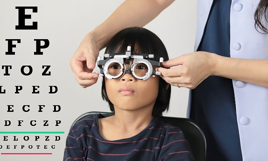 Elementary school girl wearing eyeglasses visual acuity test with test chart, eye test, Female patient checking eyesight in ophthalmology clinic, eye check