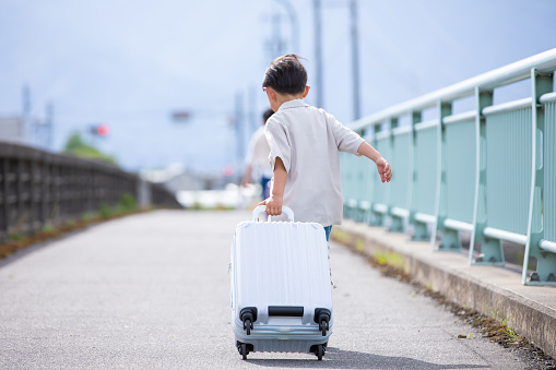 A boy walking on a bridge with a carry case