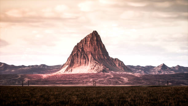 The lonely peak of the mountain, blanketed in a thick mist, makes it seem like it's floating over the fields. The power lines at the foot of the high mountains seem tiny. The mountain peak cloaked with snow and fog, standing amidst the fields, presents a captivating and mystical sight.