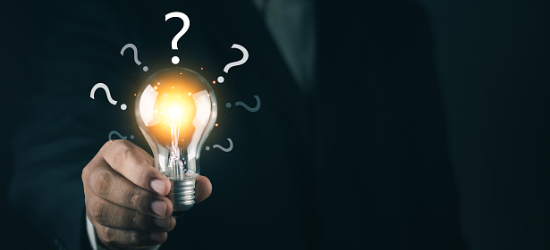 Glowing lightbulb and question mark with copy space. Businessman holding glowing lightbulb and question mark for creative thinking idea and problem solving concept.