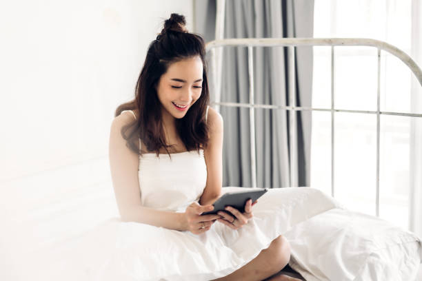 istock Happy asian woman relaxing using tablet computer on the bed at home.technology and communication concept 1491160816