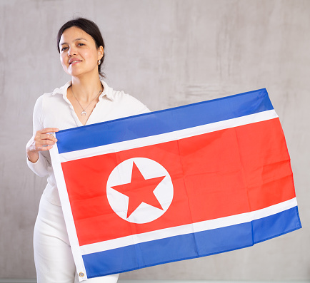 Portrait of positive young woman with the flag of North Korea