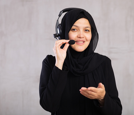 Portrait of woman in hijab helpline operator with headphones during work in call center