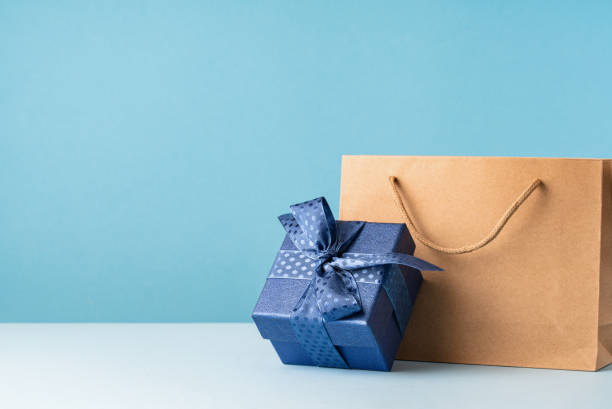 istock one gift box with a blue bow and paper bag on desk 1491164652