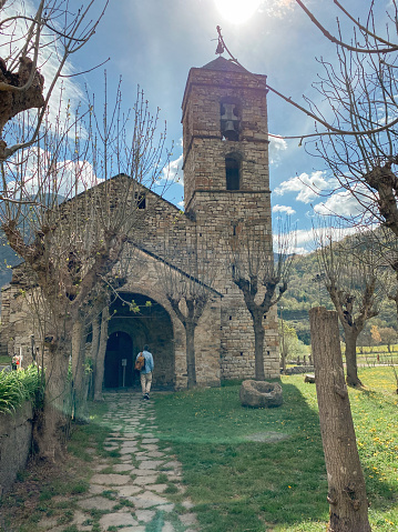 Man contemplating church of Sant Felip de Barruera. A Catalan Romanesque Church of the Vall de Boi, UNESCO World Heritage Site