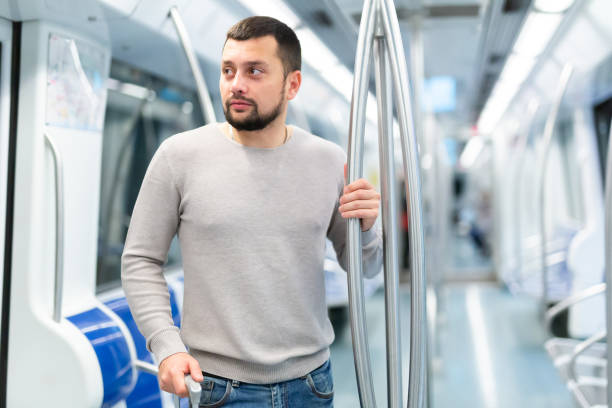 istock Bearded guy with suitcase holding on handrails in subway car 1491166601