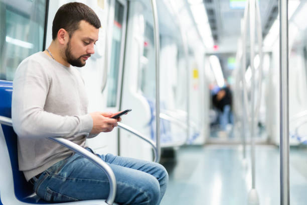 istock Young man browsing messages on phone in metro car 1491166622