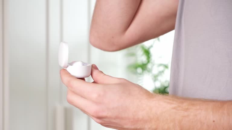 guy pulls out case and inserts wireless headphones into ears. Young man showing wireless headphones.