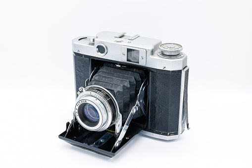 An old medium format camera with bellows lens from the 1940-50s on white background.