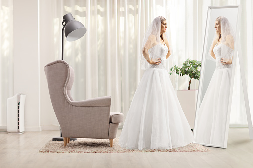 Full length profile shot of a bride standing in front of a mirror at home