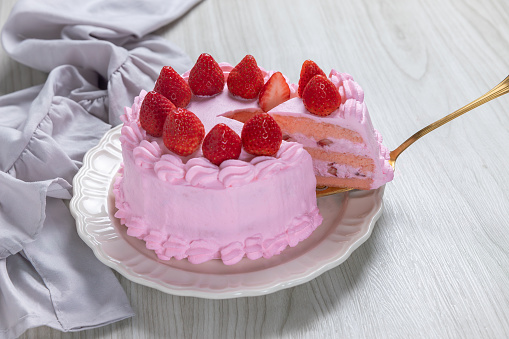 Strawberry cake, strawberry sponge cake with fresh strawberries and whipped cream on a wooden background.