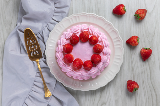 Strawberry cake, strawberry sponge cake with fresh strawberries and whipped cream on a wooden background.