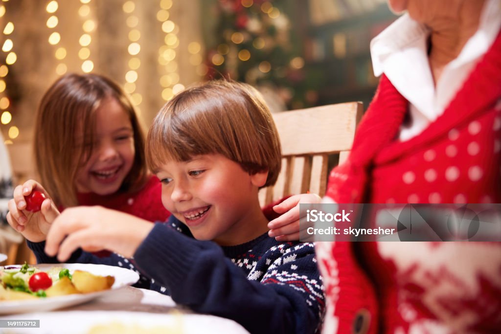 Happy Kids Enjoying In Christmas Lunch With Their Family Stock Photo