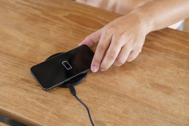 istock Charging mobile phone battery with wireless charging device in the table. Smartphone charging on a charging pad. Mobile phone near wireless charger Modern lifestyle technology concept. 1491179759