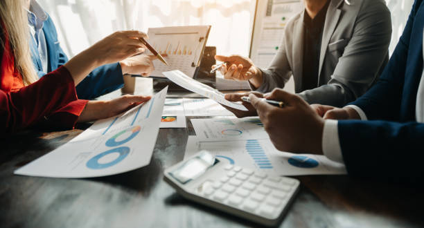 istock Business documents on office table with smart phone and calculator digital tablet and graph business with social network diagram and two colleagues discussing data working in the office 1491184951