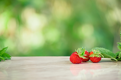 group of strawberries (hanging down) and strawberry flowers; main focus on the larger fruit in the centre (out-of-focus background)