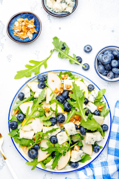 istock Gourmet summer salad with sweet pears, blueberries, blue cheese, arugula and walnuts. White kitchen table background, top view 1491185821