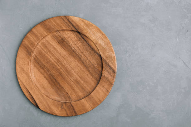 istock Wooden plate. Empty round wooden plate on gray stone background 1491186455