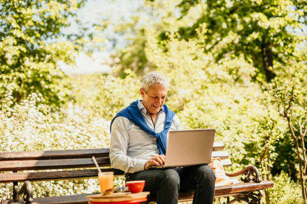 istock Handsome senior businessman taking out a laptop from his brown backpack and about to work from an outdoors cafe. 1491187055