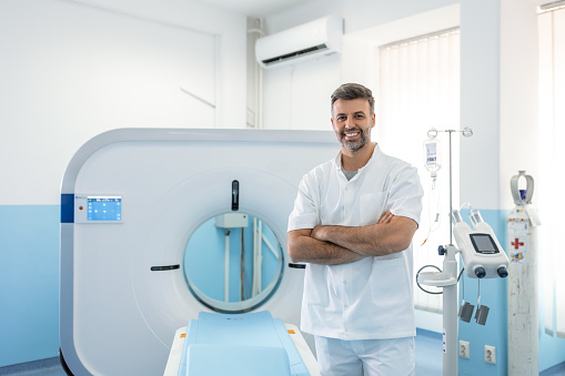 Médico oncológico masculino seguro en la sala de imágenes por resonancia magnética o tomografía computarizada de un hospital moderno. photo