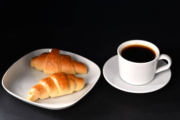 istock Croissant and coffee in white dishes on a dark background. 1491199130