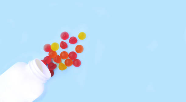 Multicolored jelly candies, vitamins scattered from a jar isolated on a blue background.