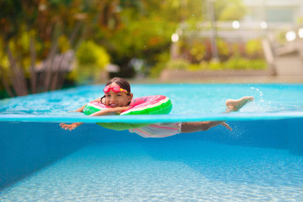 Child in swimming pool on toy ring. Kids swim.