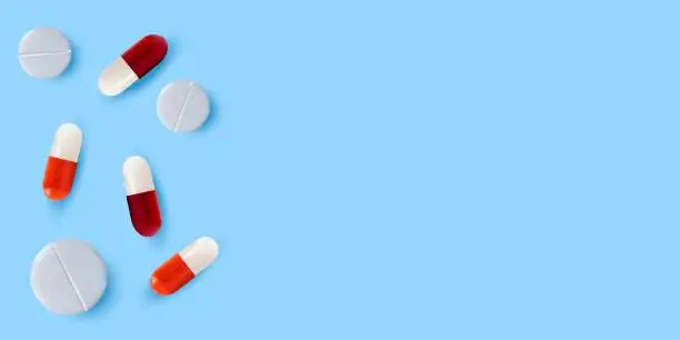 Vector illustration of White pills and red-and-white pills on a blue background. The concept of treatment and recovery. A health design element for apps, websites and social networks. Medicinal pills.