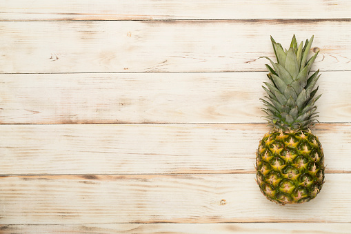 Fresh pineapple on wooden background, top view