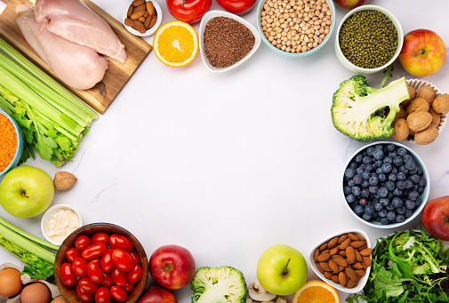 Dietary and healthy food themes. Table top view of fresh vegetables and legumes on rustic wooden table. Food is rich of fiber ideal for dieting and healthy eating. Includes corn, avocado, broccoli, orange fruit, grapes, bell pepper, lettuce, banana, apple  almonds and wholegrain pasta.