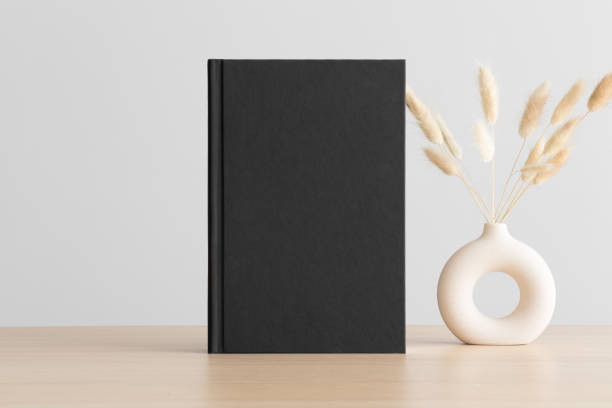 Black book mockup with a lagurus decoration on the wooden table.