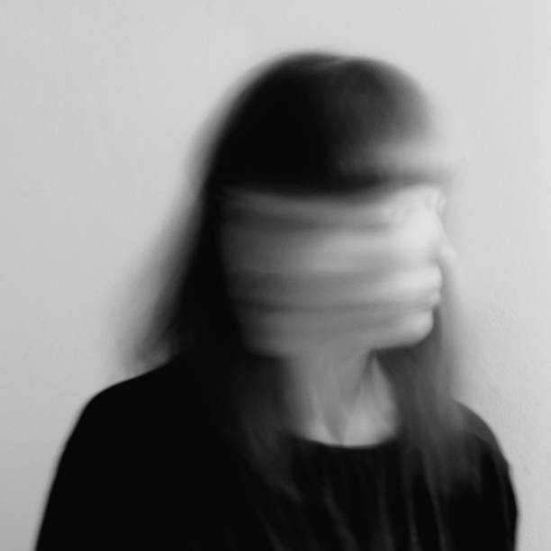 young woman moving her head fast, black and white long exposure surreal portrait - pijn fotos stockfoto's en -beelden