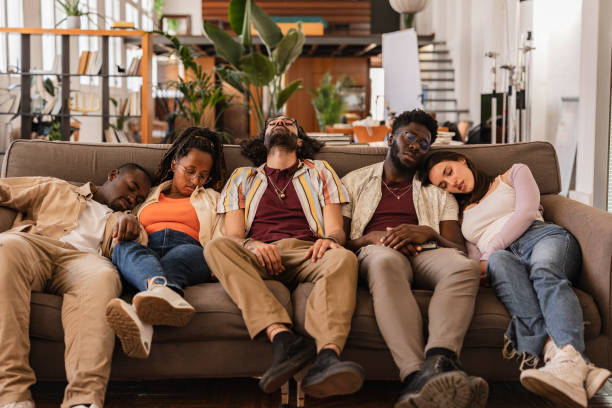 party multiracial friends, drunk and hungover sleeping on a sofa in the living room after the celebration. drinking, hangover and alcohol, coworking workers at break sleeping on the sofa - celebration drunk drinking after party imagens e fotografias de stock