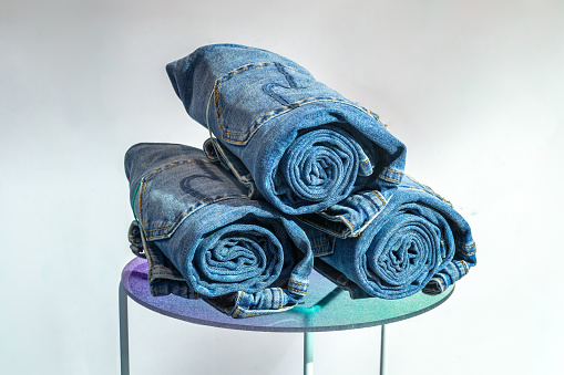 Three pairs of jeans rolled into a roll on a stool