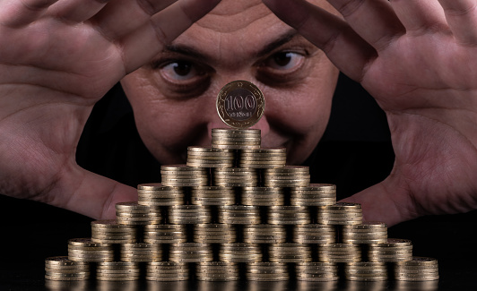 100 Kazakhstani tenge coins stacked in the form of a pyramid and mans face