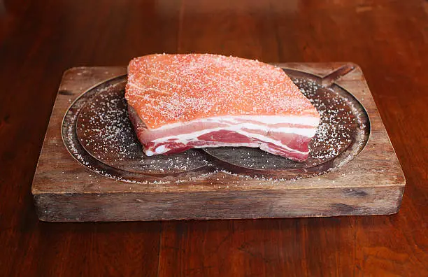 Photo of Pork belly raw and salted on a wooden tray